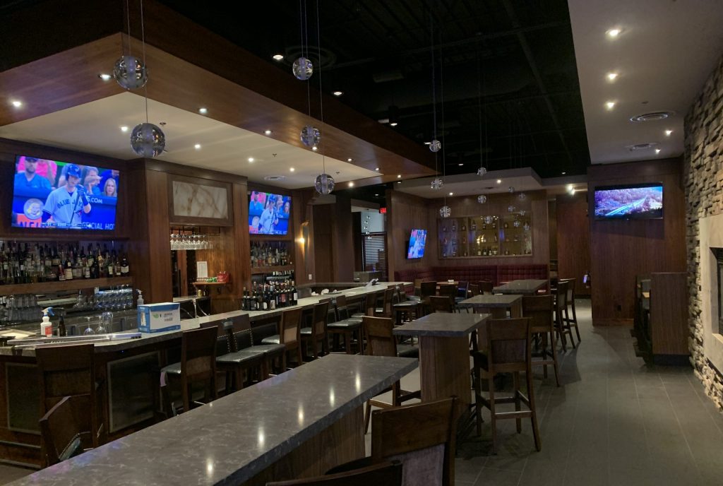 Multiple mounted televisions and installed lights in a restaurant and bar