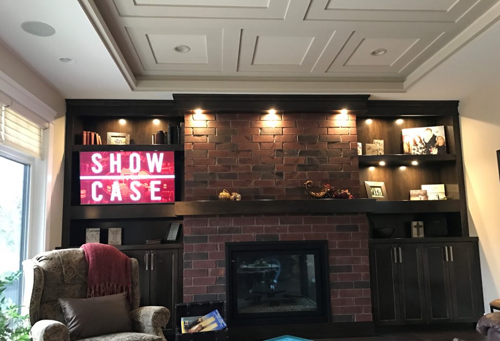 mounted television next to a brick fireplace and window