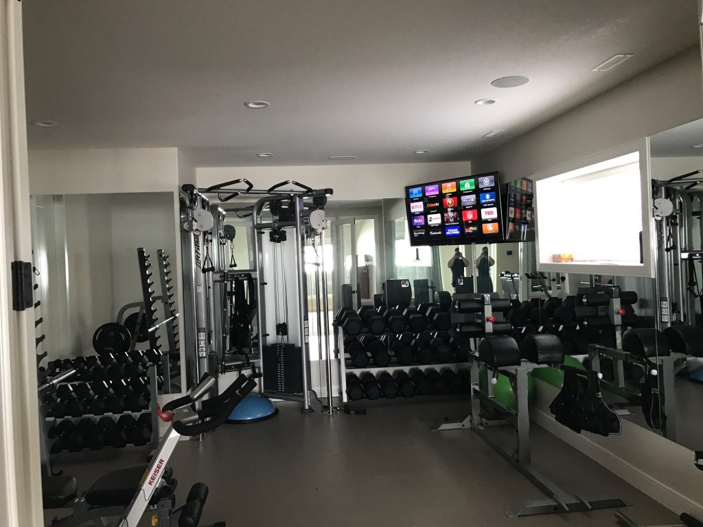 mounted tv in the corner of a home gym with a ceiling speaker