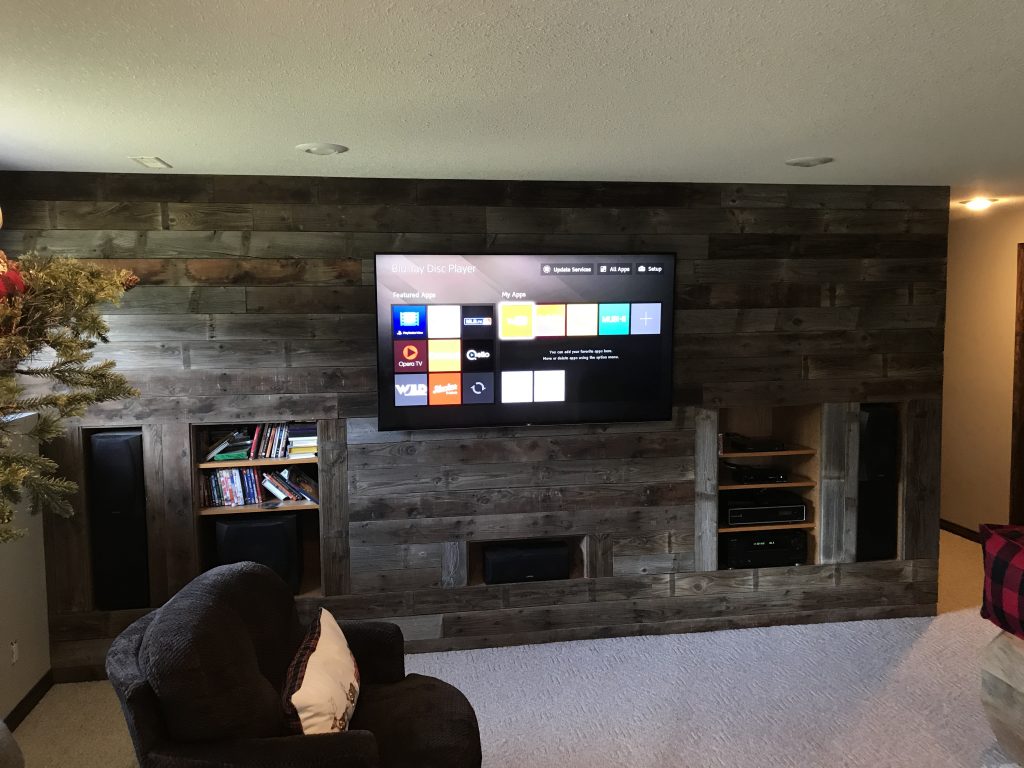 Living room theatre setup with wood wall panels and a mounted television